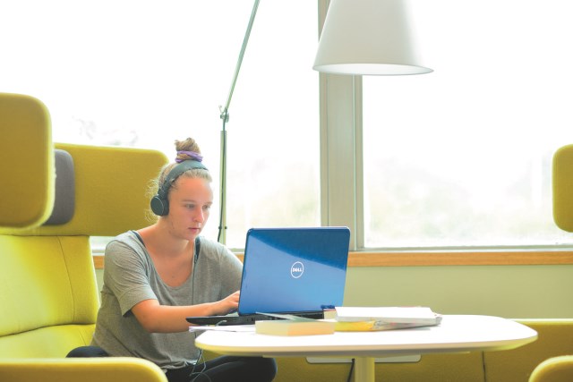 Student wearing headphones and working on a laptop