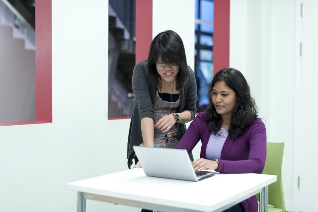 Student and tutor working together on a laptop.