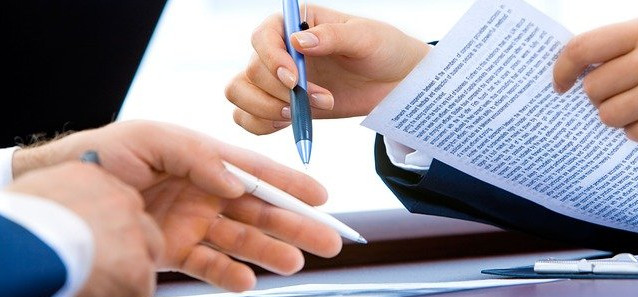 A close up of someone's hands holding a piece of paper in one hand, and a pen in the other.
