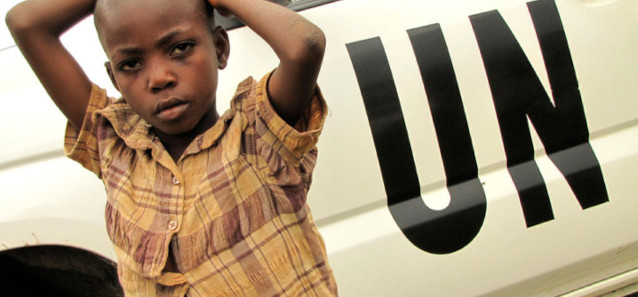 A child standing in front of a truck with "UN" painted on the side in black.